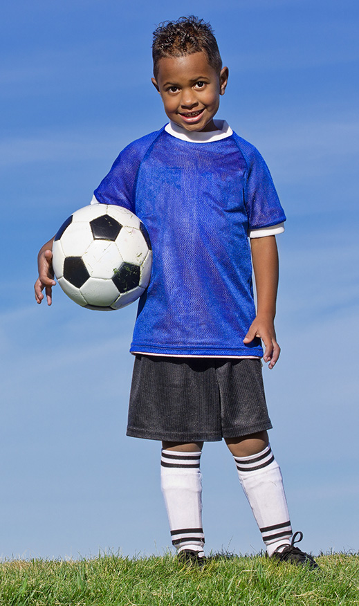 Adolescent boy in soccer uniform holding a soccer ball