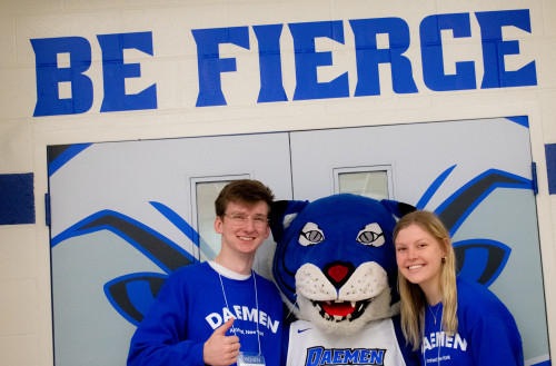 Two students with willie the wildcat standing under a 'Be Fierce' sign