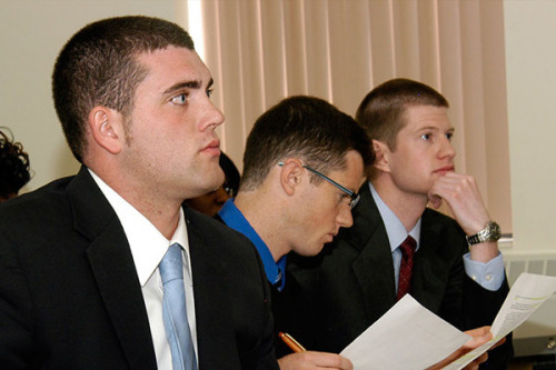 Three male business students wearing suits in class