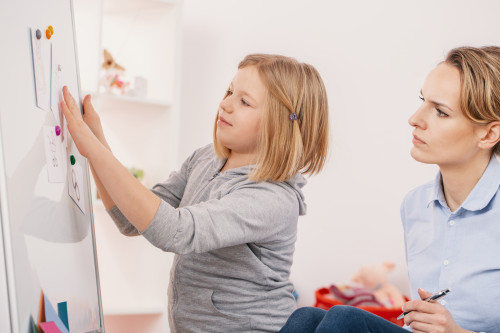 Therapist working with a child on a whiteboard