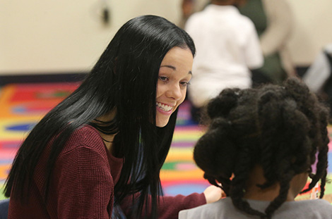 Female ABA student smiling and workin with a child.