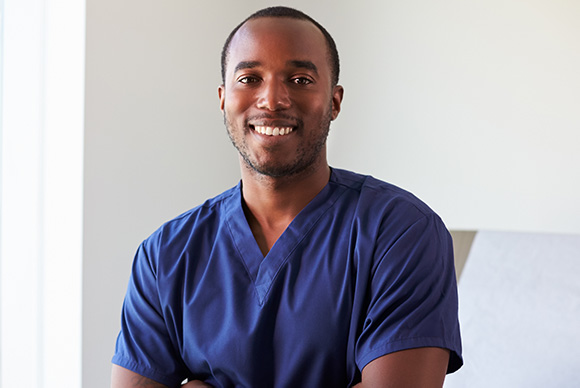 African American male in medical scrubs smiling with arms folded over chest