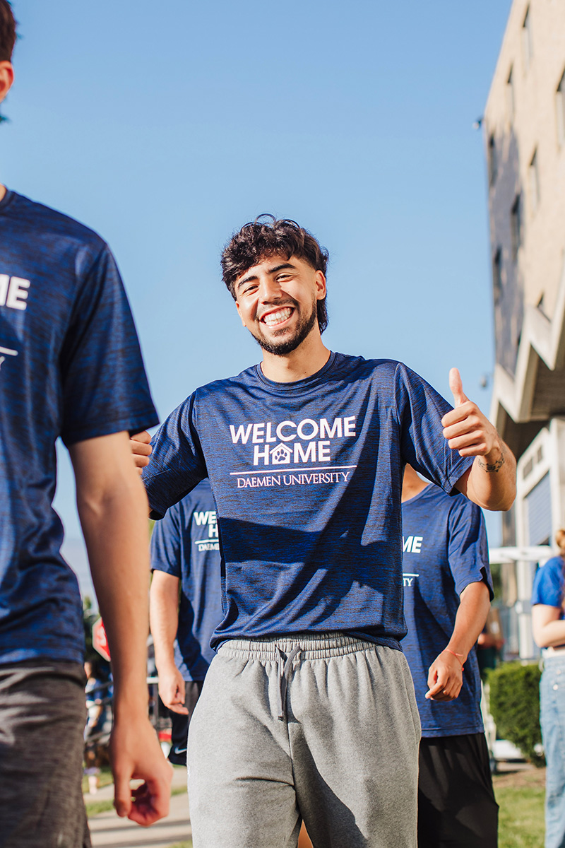 Student at Welcome back weekend holding two thumbs up and smiling 