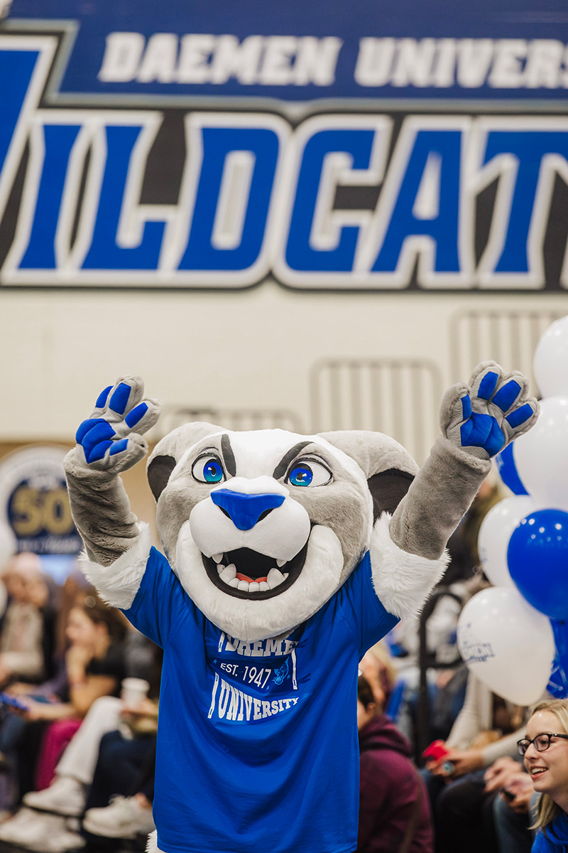 Willie the Wildcat holding arms up in Lumsden Gym