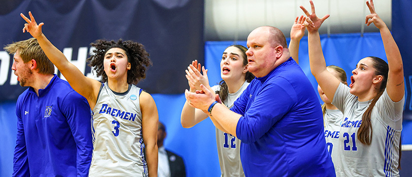 Womens basketball team and coach cheering courtside