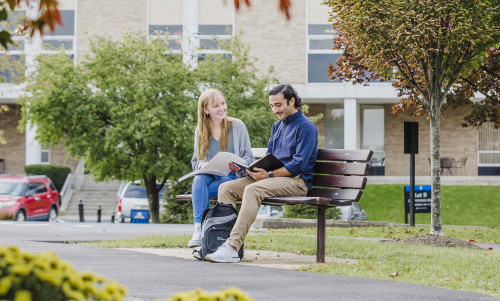Students sitting on bench reading.