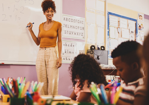 Female teacher standing in front of a whiteboard teaching grade school