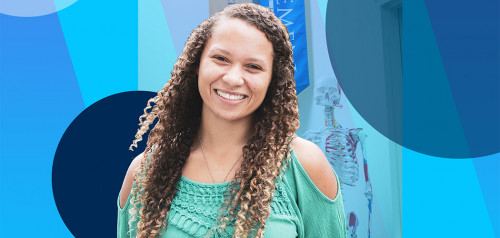 Female student standing in front of Daemen banner