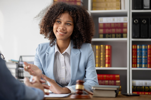 Female attorney sitting at a table, law books on a shelf behind her