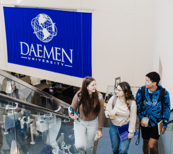 students walking up stairs in RIC, Daemen University banner hung on wall behind them