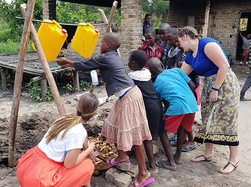 Social Work students helping kids in an African village setup a hand washing station
